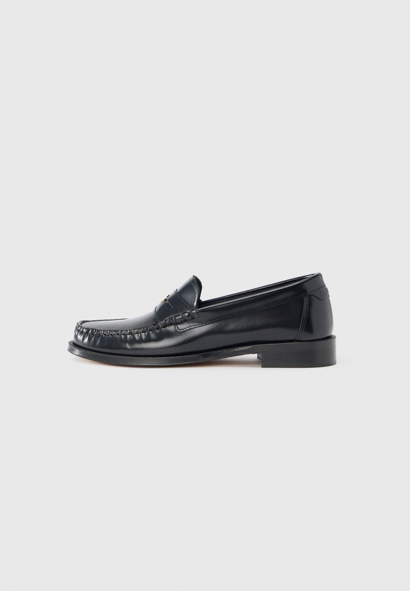 Black leather loafer featuring a rounded toe, decorative stitching, and a low block heel. Smooth texture, minimal accents.