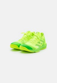 Neon zielone buty sportowe z teksturowaną cholewką, z jasnymi i ciemnymi zielonymi paskami oraz amortyzowaną podeszwą. Sznurówki w kolorze butów.