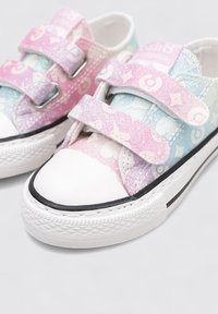 Zapatillas multicolores con tela de degradado rosa y azul, patrones de estrellas, dos tiras de velcro, punta de goma blanca y acentos en la suela negra.