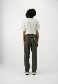 Grijze cargobroek met elastische tailleband, zakken en een zachte textuur. Gepaard met een eenvoudig wit shirt met korte mouwen.