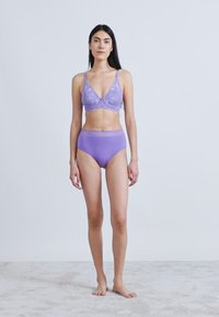 Fialková krajková braletka s nastavitelnými ramínky a odpovídajícími kalhotkami s vysokým pasem. Hladká, elastická látka s jemnými detaily na pásku.
