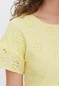 Geel katoenen topje met bloemvormige uitsnijdingen, korte mouwen, een ronde halslijn en een gestructureerde stofafwerking.