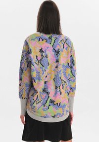 Mönstrad tröja i flera färger med ett livligt abstrakt mönster i nyanser av blått, rosa, gult och grönt; har en grå nederkant och ärmar.