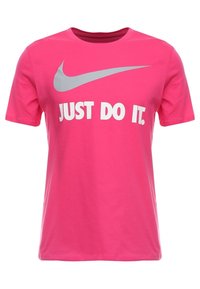 Rosa kortärmad t-shirt i bomull med rund halsringning. Har en stor grå Nike-swoosh och vit text som säger "JUST DO IT."