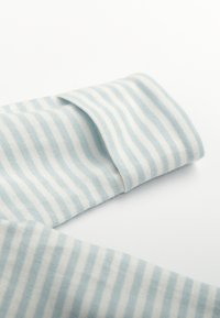 Tissu en coton rayé dans des tons bleu clair et blanc, présentant une texture douce avec des lignes horizontales visibles et un bord plié.