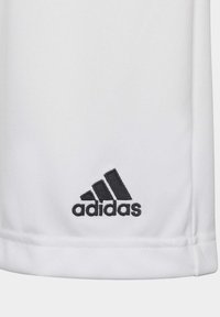 Camisa deportiva de tela blanca con el logo bordado en negro de "adidas" en la esquina inferior izquierda. Textura suave, mangas cortas, diseño sencillo.