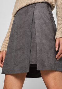 Grijze suède skort met plooien, met een gladde textuur en een uitlopende vorm. De stof ziet er zacht uit en heeft een matte afwerking.