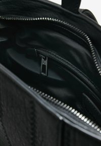 Schwarze Handtasche mit einem glatten Stofffutter, einer Reißverschluss-Tasche und silbernen Hardware-Details. Entwickelt für einfachen Zugang und Organisation.