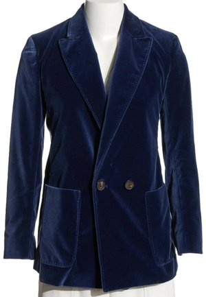 Blazer cruzado de terciopelo azul marino con solapas anchas y dos bolsillos delanteros parche en un maniquí blanco.