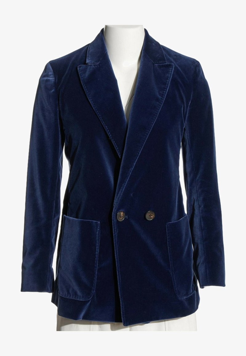 Blazer croisé en velours bleu marine avec larges revers et deux poches plaquées devant sur un mannequin blanc.