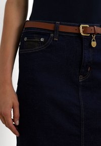 Gonna in denim scuro con un design dritto, cintura in pelle marrone con fibbia dorata e cuciture delle tasche in evidenza.