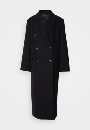 Cappotto in lana nero doppiopetto con colletto a scialle, due tasche frontali e grandi bottoni di chiusura, caratterizzato da un taglio lungo e dritto.