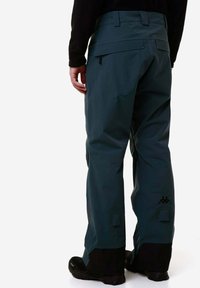 Pantaloni da neve impermeabili di colore verde scuro con una vestibilità comoda, dotati di vita regolabile e dettaglio del logo nero vicino alla caviglia. Presenti also rinforzi alle estremità.