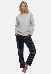 Lichtgrijs langslievend shirt gecombineerd met marineblauwe broek met witte verticale strepen, ontworpen voor comfort met een ontspannen pasvorm.