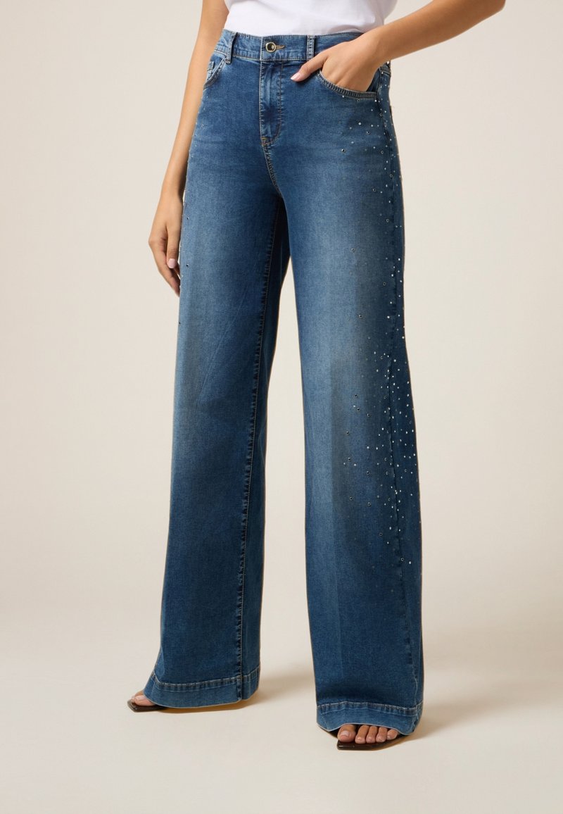 Lage blauwe denim jeans met wijde pijpen, een hoge taille, subtiele glinsteraccenten en twee voorzakken, die het casual ontwerp versterken.