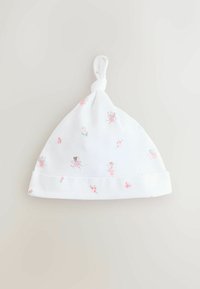 Bonnet bébé en coton blanc avec un nœud au sommet, orné de motifs de fées et de fleurs pastel roses sur le corps et le bord.