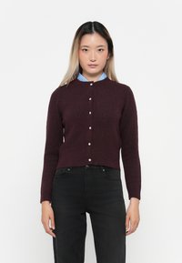 Cardigan bordeaux en maille douce, avec un col rond, des manches longues et des boutons argentés sur le devant.