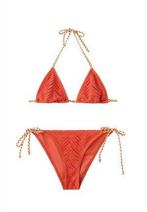 Conjunto de bikini de crochet rojo anaranjado con top de cuello halter anudado y braga triangular con lazos laterales, con tiras trenzadas sobre fondo blanco.