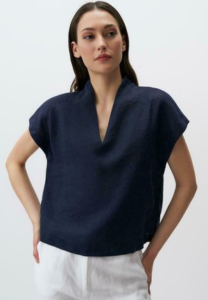 Top en lin bleu marine avec un décolleté en V et des manches courtes. Le tissu a une texture subtile, avec une coupe décontractée et un ourlet droit.