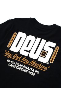 Black cotton t-shirt featuring bold white and orange text: "DEUS PARTS SERVICE" and "Any God Any Machine," with address details below.