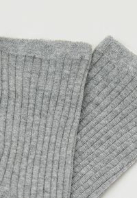 Calcetines gris de canalé con una textura suave, que cuentan con un puño doblado y un patrón de canalé vertical para mayor elasticidad y comodidad.