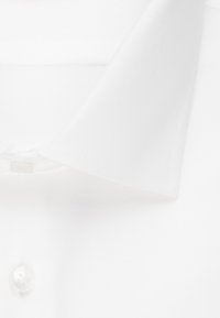 Chemise blanche à col classique, présentant une texture de tissu lisse, une fermeture à boutons et des détails de couture raffinés.