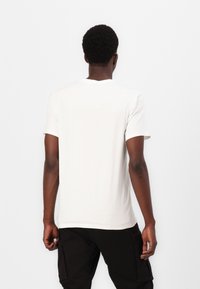 Bílý krátký rukáv tričko vyrobené z bavlny, s klasickým kulatým výstřihem. Střih je pohodlný, s hladkou a jemnou texturou.