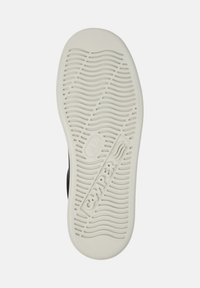 Sole of a white Camper shoe with wavy tread patterns and the brand name embossed in the center.