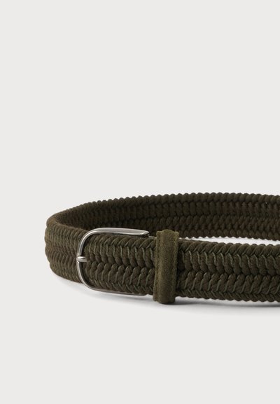 Ceinture en tissu vert foncé tressée avec boucle en métal argenté et boucle en tissu assortie sur un fond clair uni.