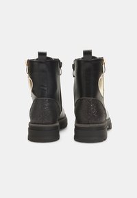 Botas de cuero negro hasta el tobillo con un tacón negro brillante, cierre de cremallera lateral y un acento blanco en contraste en el lateral. Detalles de superficie texturizada.