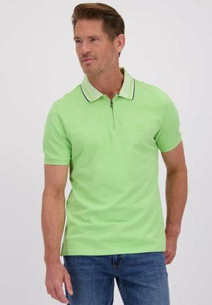 Lichtgroene polo met rits, gestructureerde kraag met een contrasterende bies, gecombineerd met blauwe spijkerbroek.