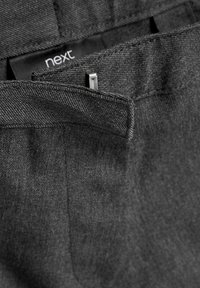 Tessuto di denim grigio scuro con una consistenza liscia. Presenta un accento metallico e un'etichetta che riporta la scritta "next" all'interno della cintura.