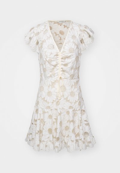 Balta kleita ar pūkainām piedurknēm, kas rotāta ar izšūtām margrietiņu zīmēm un un ar aukliņu priekšpusi. Paplatināta svārku daļa ar viļņotu apakšmalu.