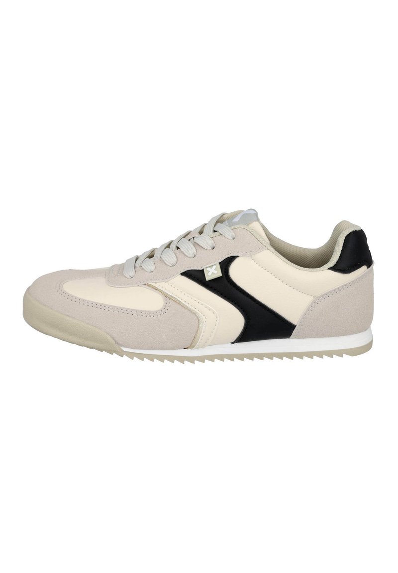 Zapatilla beige y negra con material de ante y sintético, puntera redonda, suela texturizada y cordones tono sobre tono. Presenta un sutil detalle del logo en el costado.