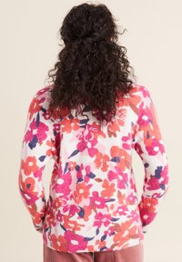 Blumenpullover in Weiß mit pinken, orangefarbenen und marineblauen Mustern. Weicher Stoff und lockere Passform. Mit langen Ärmeln und rundem Ausschnitt.