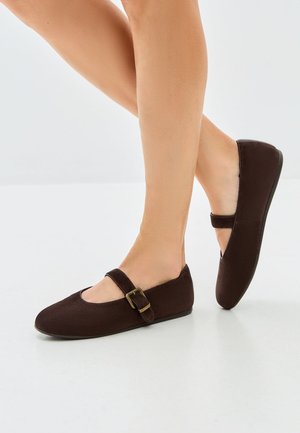 Brązowe płaskie buty z okrągłym noskiem, z klamrą na wierzchu stopy. Gładka tekstura i minimalistyczny design. Cienka podeszwa.