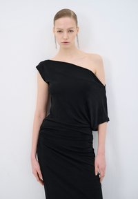 Sort off-shoulder kjole med tætsiddende overdel og rynkede detaljer; lavet af letvægtsstof, glat tekstur, smuk fald.