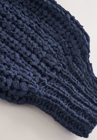 Un textile tissé bleu marine présente un motif texturé avec des bandes entrelacées, offrant une finition douce et des détails côtelés le long des bords.