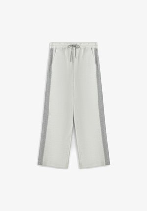 Pantalon ample en polaire gris clair avec bandes latérales gris foncé, taille élastique et fermeture à cordon, posé à plat sur fond blanc.