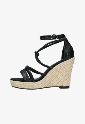 Mustat viistot sandaalit, joissa on teksturoitu päällinen, koristeltu kudotuilla remmeillä ja nilkkahihnalla. Viisto on valmistettu luonnollisesta köysimateriaalista.