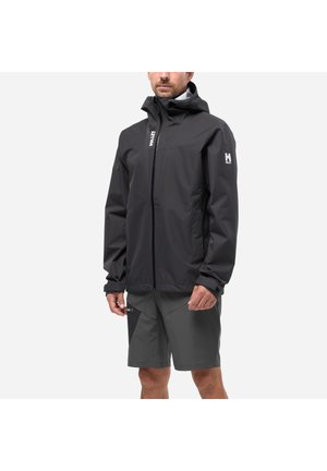 Man wearing black hooded waterproof jacket and dark gray shorts against a plain light background.