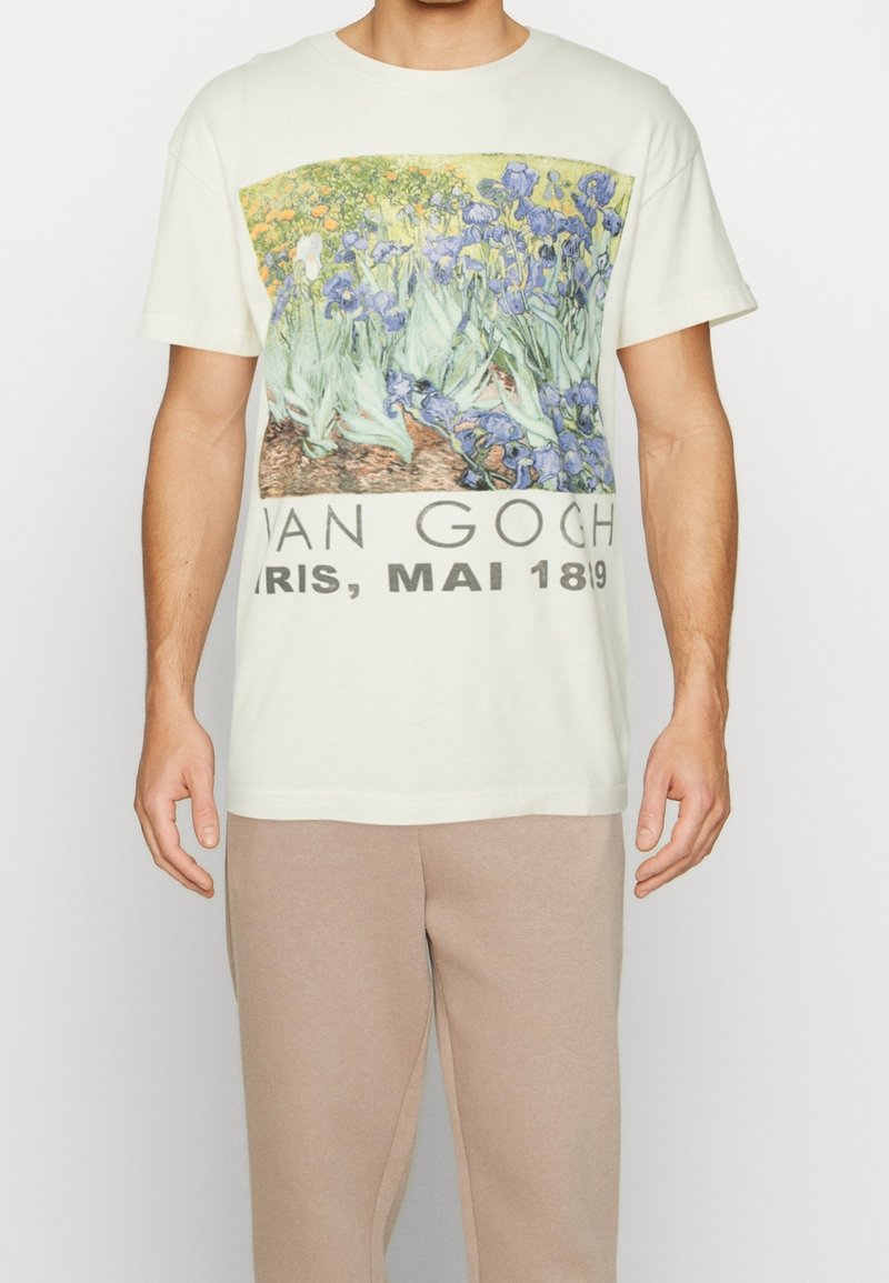 Lyhythihainen kermaisempi puuvillainen t-paita, jossa Van Goghin iiriksen kuvio ja teksti "VAN GOGH, PARIS, MAI 1819" alareunassa.