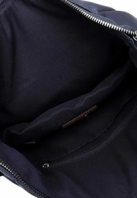 Merevaigist sinine kott, mille sees on sile tekstuur, lukuga tasku ja veel üks tasku. Puhtad jooned, minimaalne riistvara.