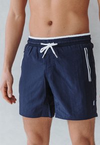 Marineblauwe zwemshorts gemaakt van lichtgewicht materiaal, met een elastische tailleband, verstelbaar trekkoord en witte met rits afsluitbare zijzakken.