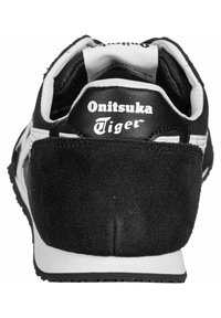 Black sneaker with suede and leather materials, featuring white stripes, a round toe, and the "Onitsuka Tiger" logo on the heel.