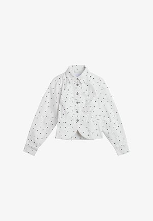 White button-up jacket with long sleeves and black polka dots, featuring a collar and fitted waist detail.