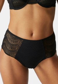 Schwarze Spitzen-Hüfthosen mit filigranen Wellenmustern, einer Mischung aus transparenten und soliden Stoffen sowie weichen, gewellten Kanten.