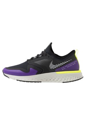 Sort og lilla Nike løbesko med hvid sål, gul hælflap, mønstret swoosh og tekst "Nike Run Utility Shield Model Odyssey React".