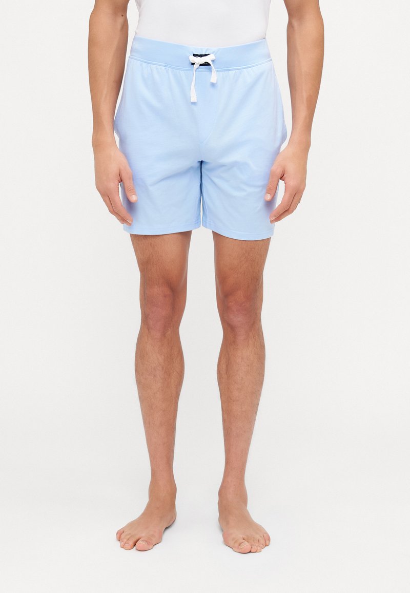 Calções de banho de um azul claro com uma cintura elástica, cordão branco e uma textura suave. Comprimento até à coxa, sem padrões visíveis.