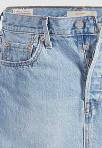 Lyseblå denimskjørt med høy midje, fem-lommer design og kobberdetaljer. Har falmet tekstur og opprevne hem detaljer.